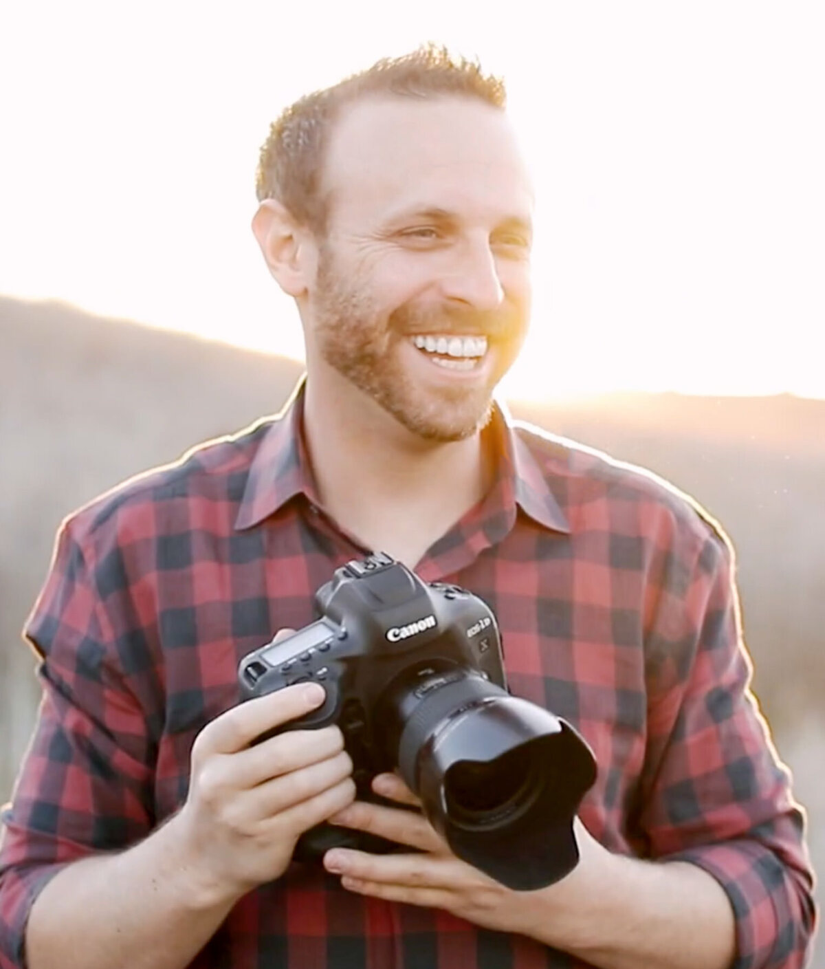 Brett Hickman at golden hour, holding his Canon camera