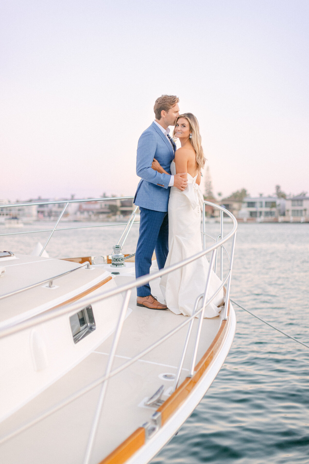Bride and groom on the bow of a classic yacht in Newport Harbor