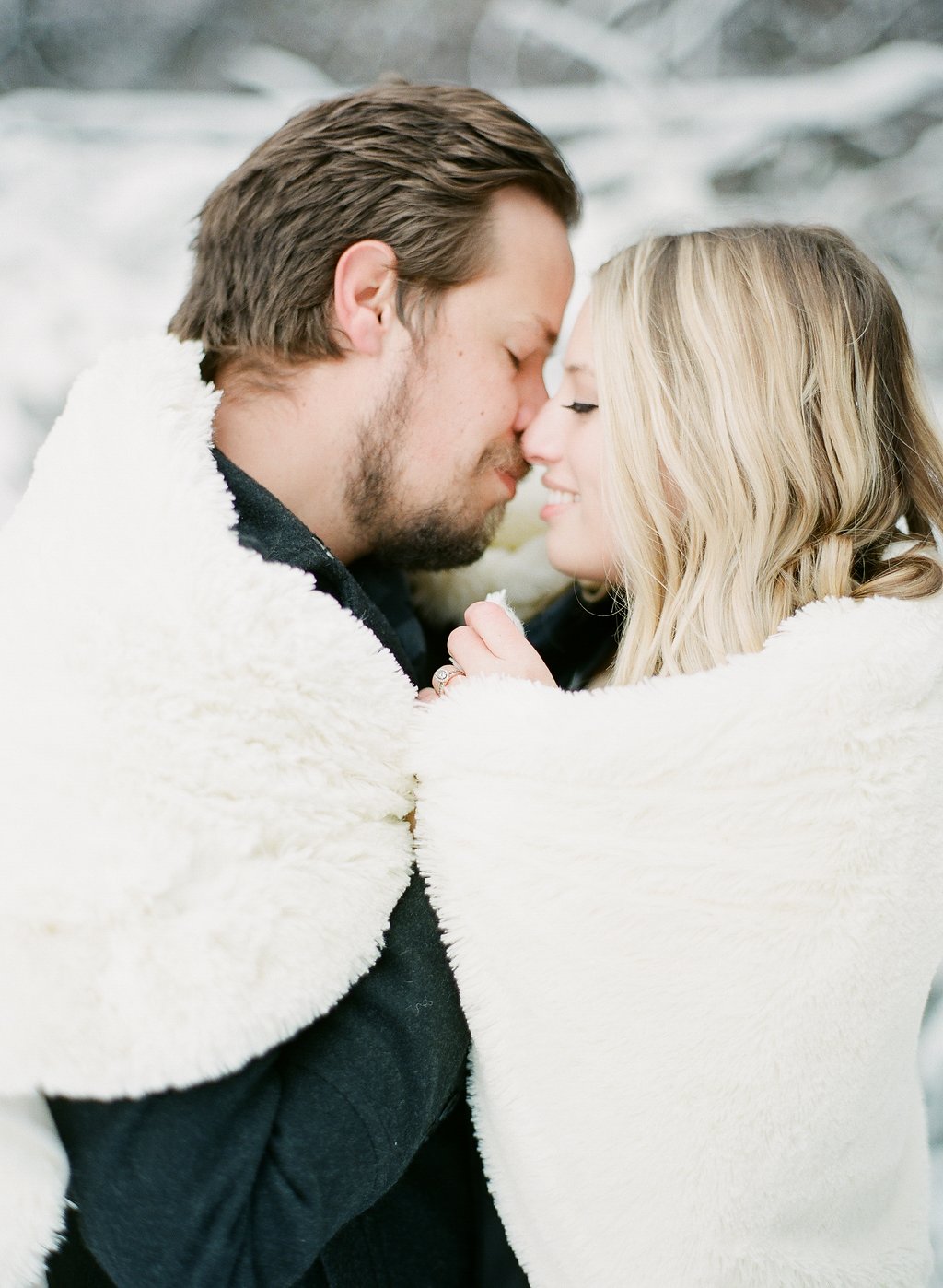 James and Cynthia nose to nose, wrapped in a white fur blanket in the snow